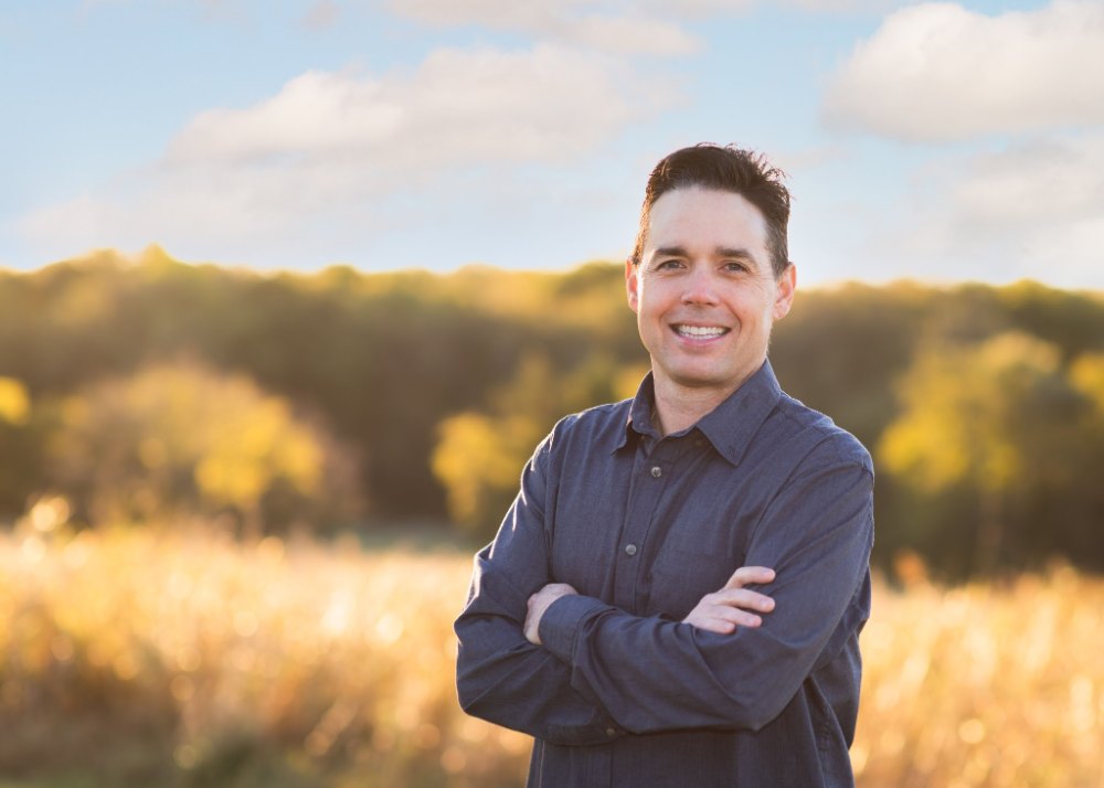Dr. Paul Chabot in a casual shirt, arms crossed, in a field